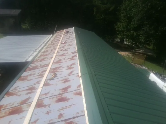 Old rusted panels beside newly installed green metal roofing — Wind Damage Roof Repair by Roofing Brothers in Knierim