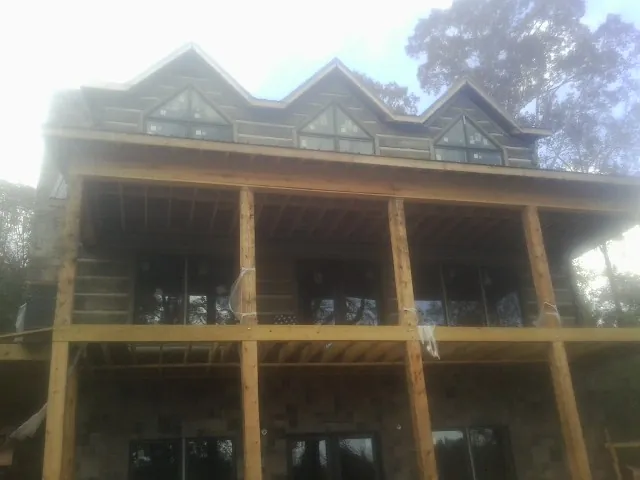 Dormers and porch framing on a large log home under construction — Roof Coating work by our crew in Knierim