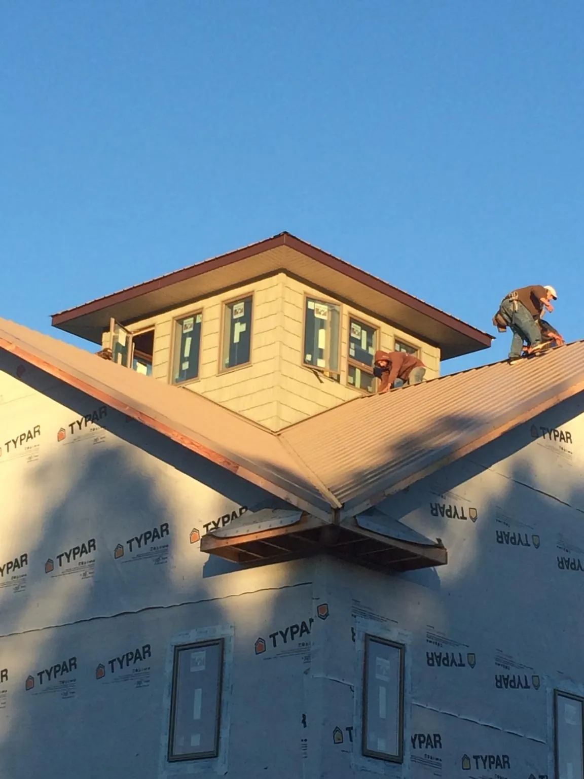 Roofers working around a rooftop cupola on a new metal roof at sunset — Roof Waterproofing in Knierim by Roofing Brothers